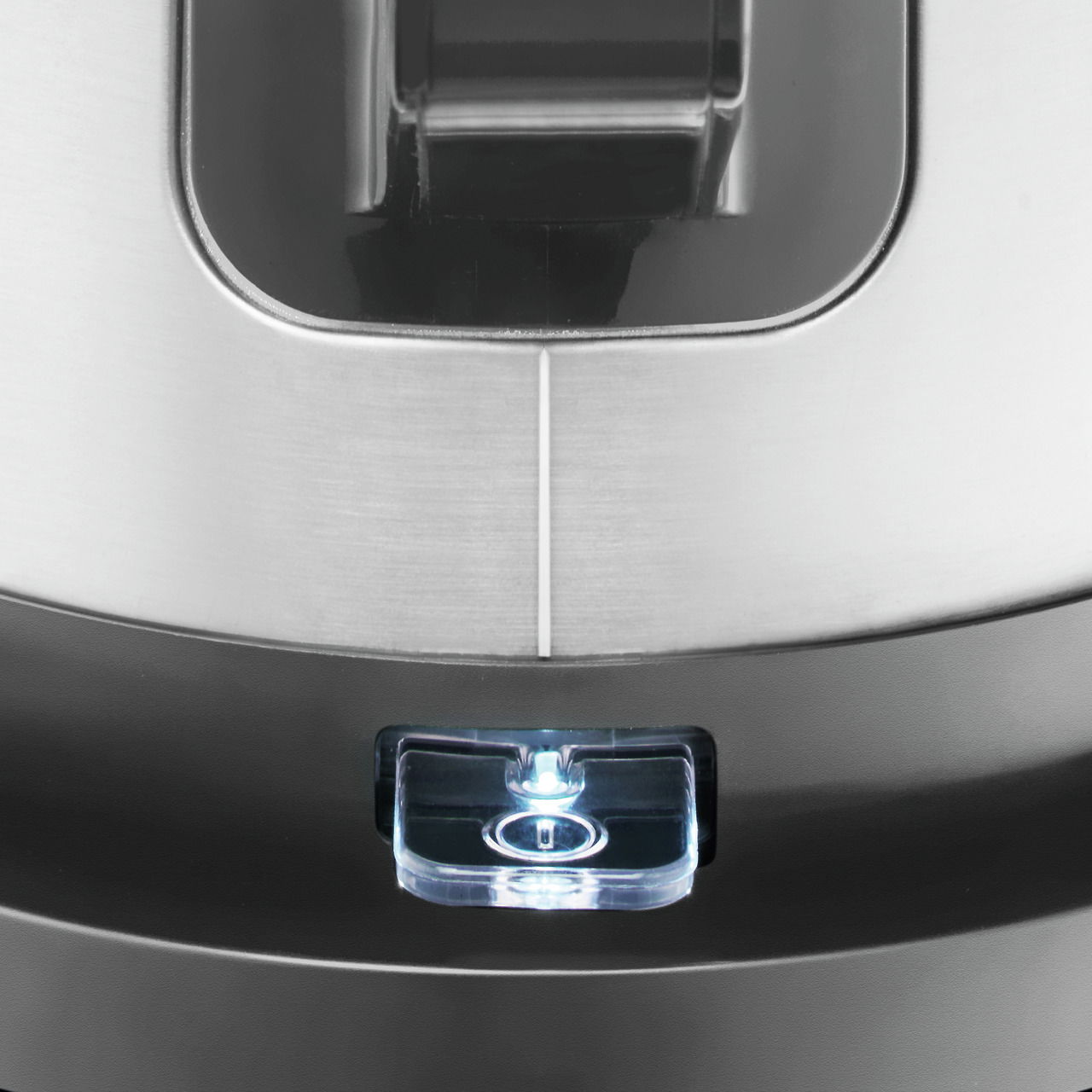 Nahaufnahme eines Wasserkochers mit Edelstahloberfläche und beleuchtetem Schalter, von oben betrachtet.