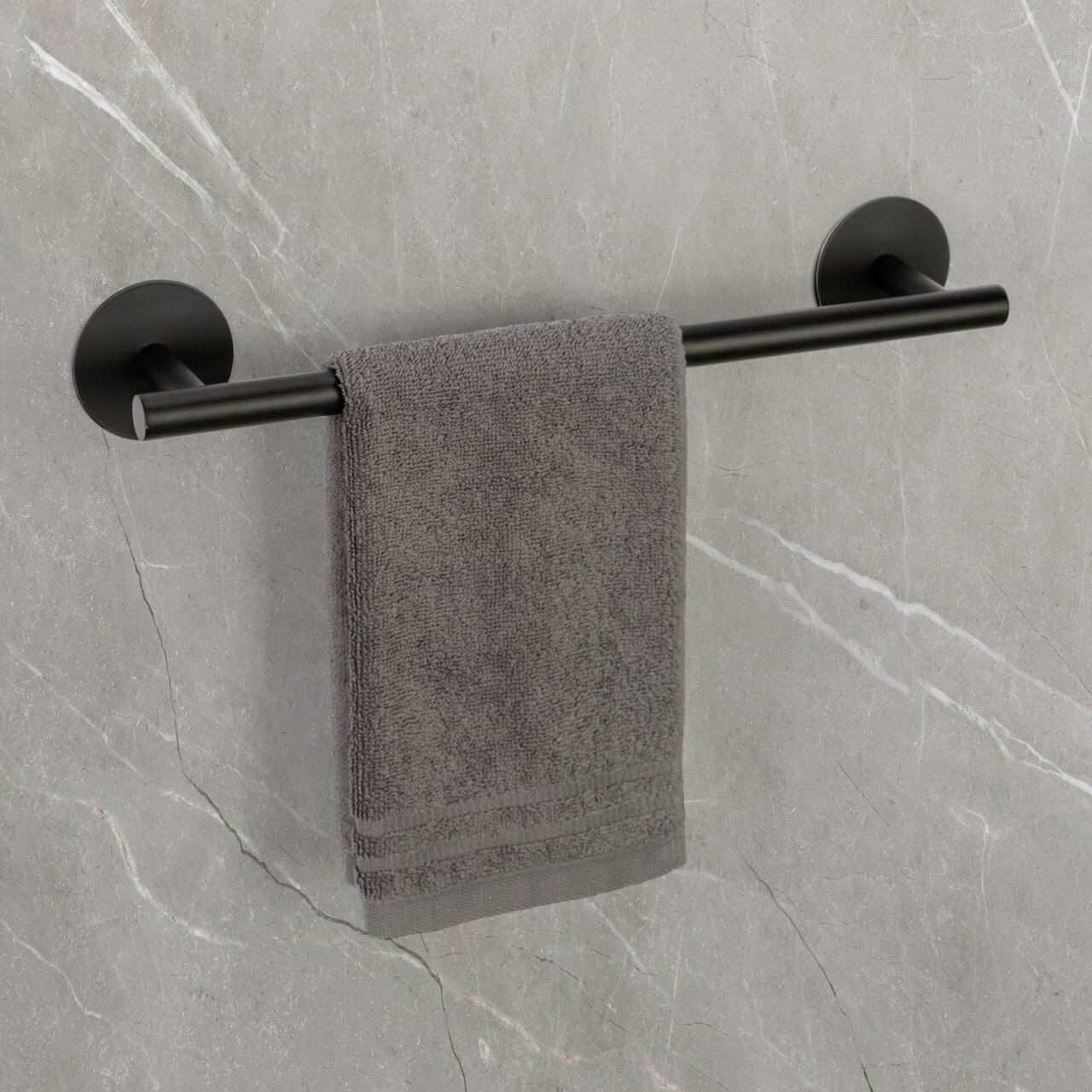Zwarte handdoekstang Uno 40 cm met grijze handdoek, bevestigd aan een grijze stenen muur, zijaanzicht