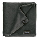 Dunkelgraues Frottierset, bestehend aus einem gefalteten Handtuch mit sichtbarem Etikett, aus der Vogelperspektive fotografiert.