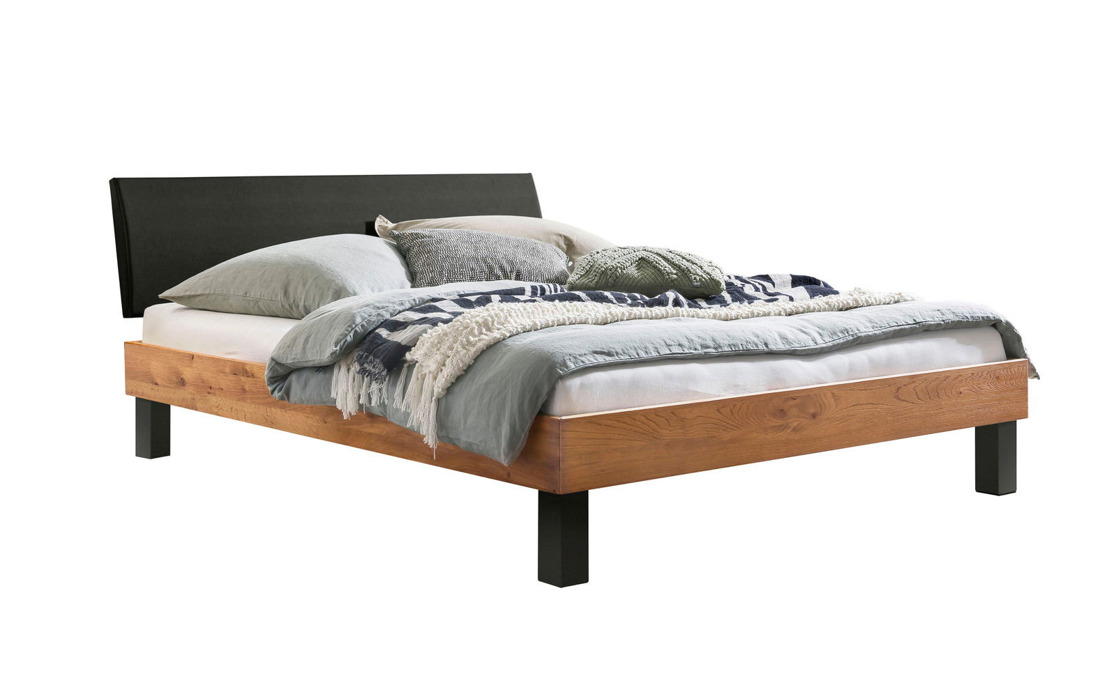 Gepolstertes Kopfteil in modernem Design, seitliche Perspektive auf ein Bett mit Holzrahmen und dekorativen Kissen.