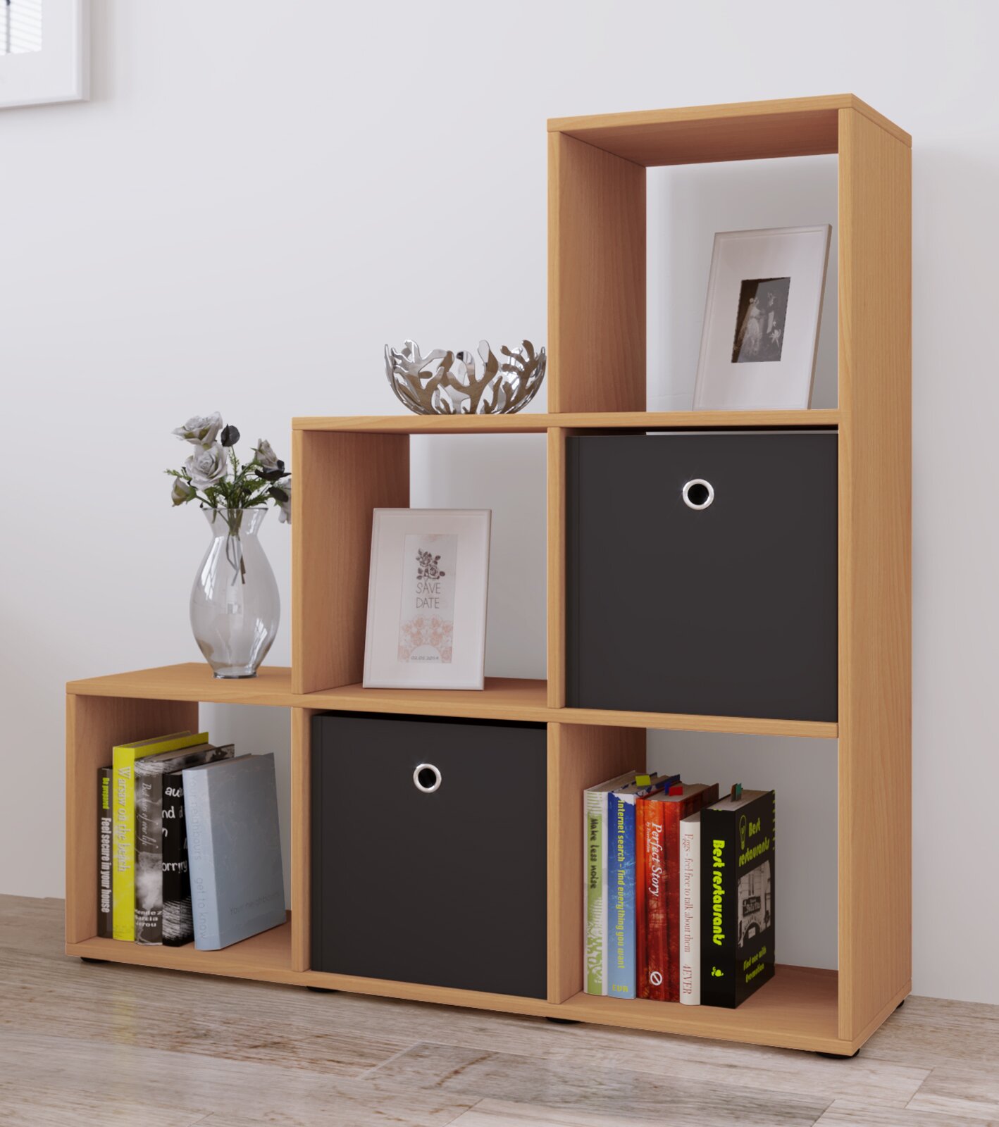 Modernes, asymmetrisches Holzregal in Eichenoptik mit offenen Fächern, zwei schwarzen Aufbewahrungsboxen und Büchern, fotografiert in schräger Frontansicht im Wohnraum.