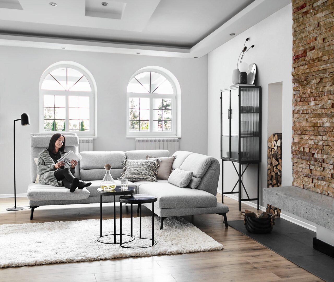 Gemütliches Ecksofa Dieter Knoll COSIO in einem modernen Wohnzimmer, seitliche Perspektive, mit einer Person, die ein Buch liest.