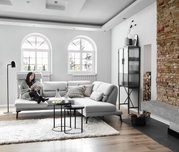 Gemütliches Ecksofa Dieter Knoll COSIO in einem modernen Wohnzimmer, seitliche Perspektive, mit einer Person, die ein Buch liest.