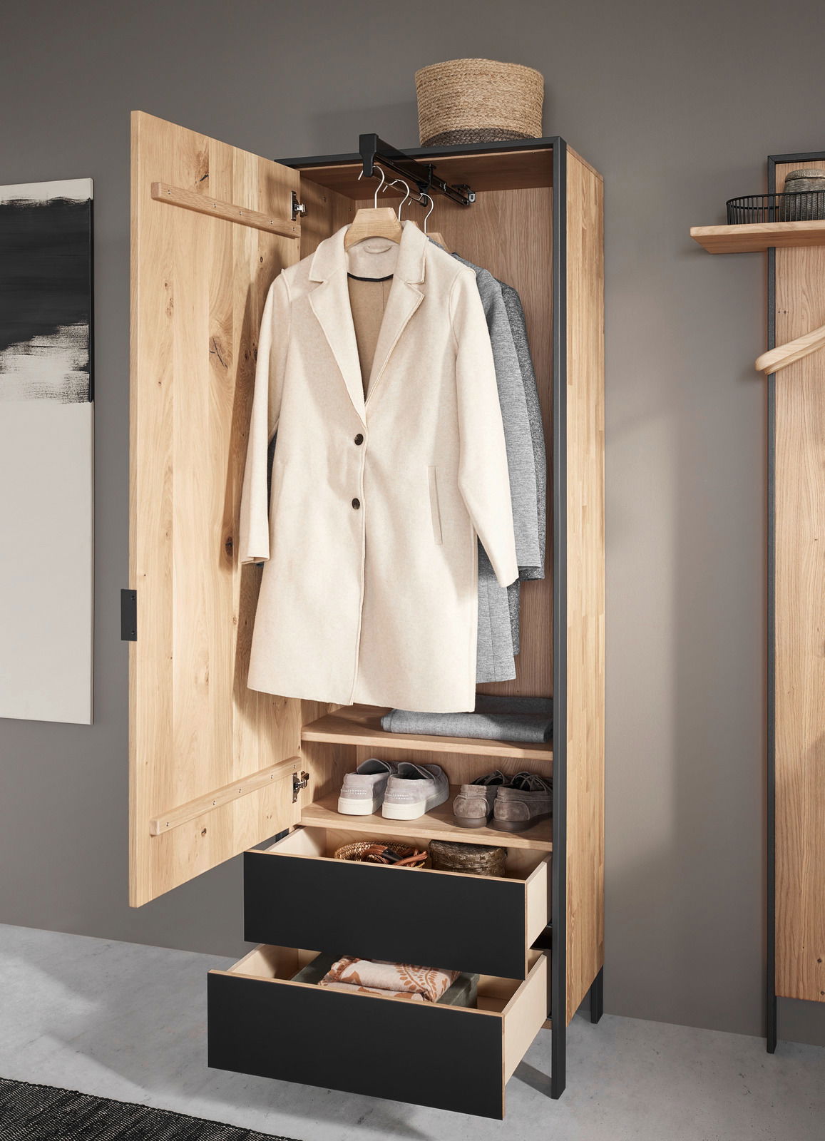 Garderobenschrank aus Holz mit geöffneter Tür, zeigt hängende Mäntel, Regale mit Schuhen und zwei offene Schubladen, Perspektive von vorne.