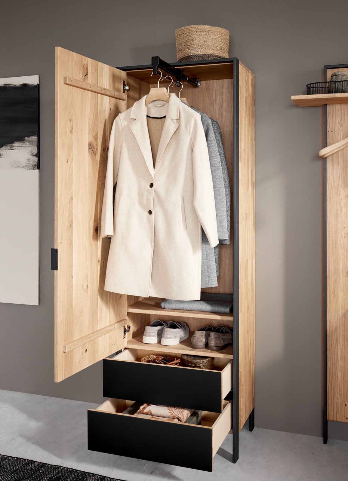 Garderobenschrank aus Holz mit geöffneter Tür, zeigt hängende Mäntel, Regale mit Schuhen und zwei offene Schubladen, Perspektive von vorne.