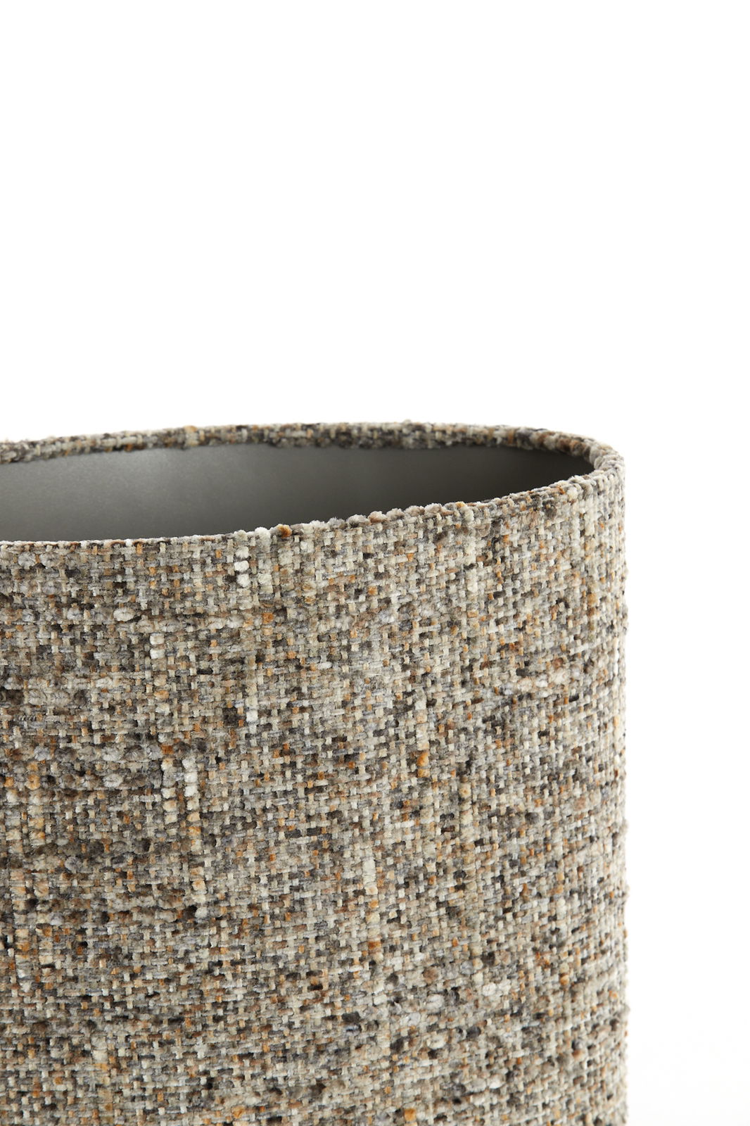 Nahaufnahme eines zylindrischen Lampenschirms mit texturierter, gewebter Oberfläche in neutralen Farbtönen, seitliche Perspektive.