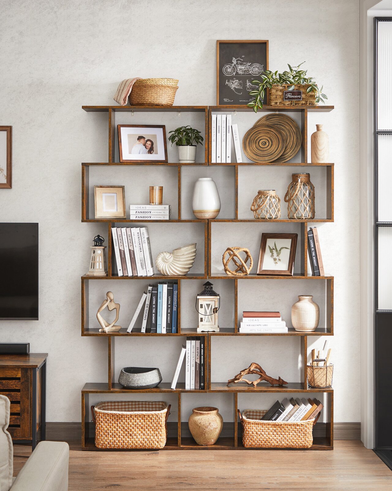 Frontale Innenraumaufnahme eines großen, asymmetrischen Regal-/Bücherregals aus Holz mit vielen offenen Fächern, dekoriert mit Büchern, Körben, Pflanzen, Bildern und Vasen.