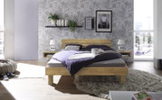 Modernes Schlafzimmer mit einem Kopfteil aus Holz und Metall, frontal betrachtet. Das Bett ist mit lila Bettwäsche bezogen und steht auf einem flauschigen Teppich. Die Wand ist mit einem Blattmuster tapeziert und dekoriert mit Pflanzen und Bildern.