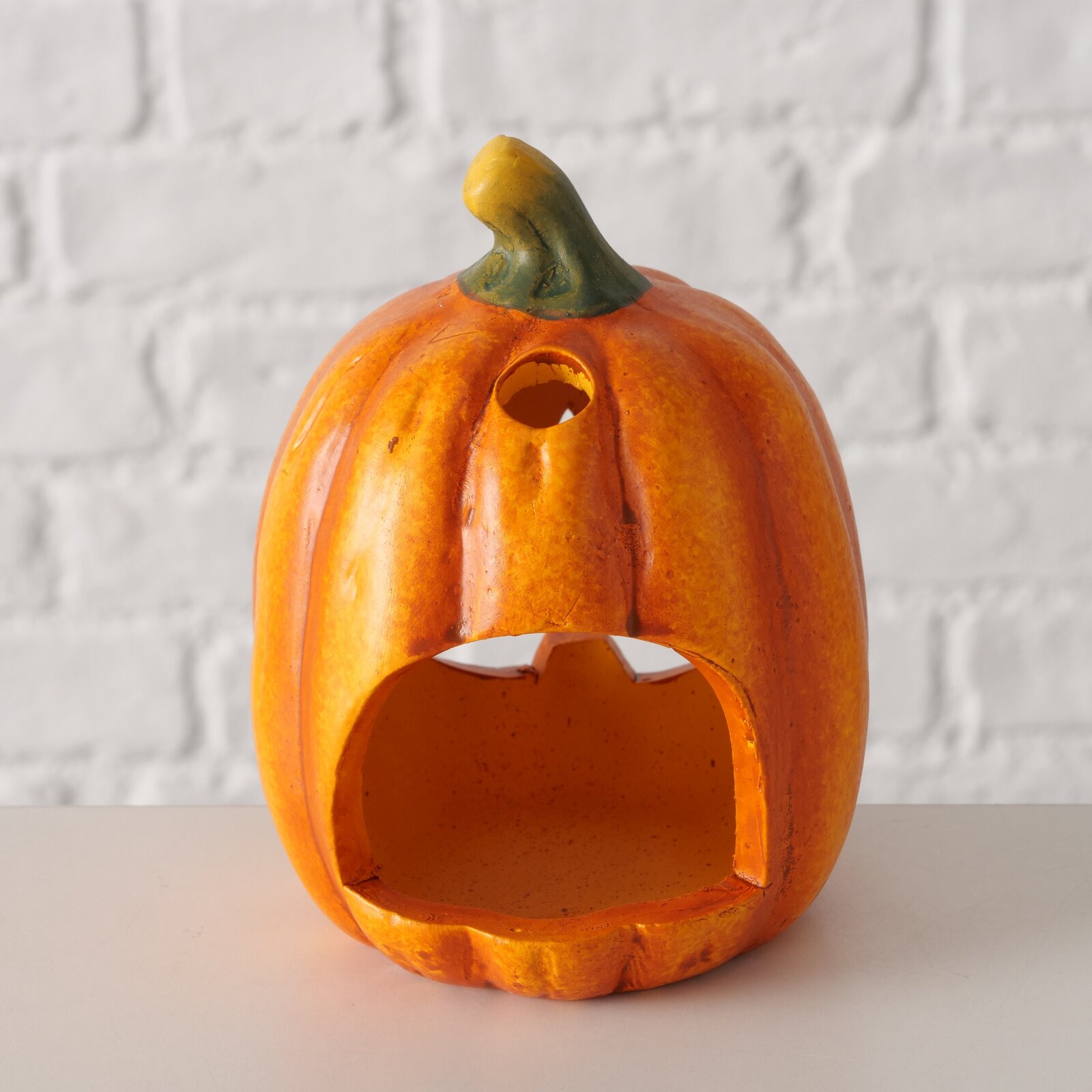 Teelichthalter in Form eines Kürbisses, frontal fotografiert, mit einer großen Öffnung vorne und einem kleinen Loch oben.