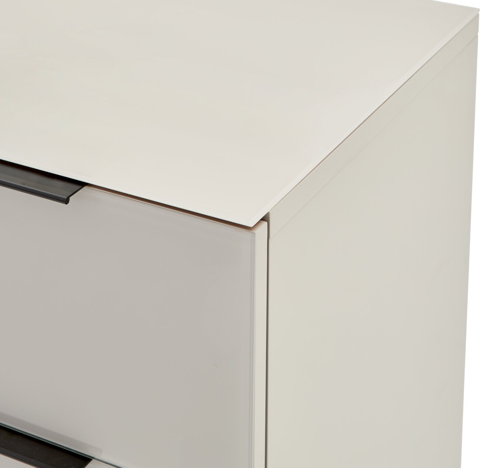 Detailaufnahme eines weißen Schranks mit Glasplatte oben und dunklem Griff, perspektivisch von schräg oben vorne