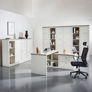 Moderne Büromöbel in heller Holzoptik, bestehend aus einem Eckschreibtisch, einem Bürostuhl und mehreren Aktenschränken, seitliche Perspektive