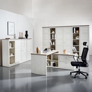 Moderne Büromöbel in heller Holzoptik, bestehend aus einem Eckschreibtisch, einem Bürostuhl und mehreren Aktenschränken, seitliche Perspektive