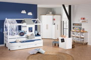 Kinderzimmer mit einem weißen Hausbett mit grauem Dach, umgeben von blauen und weißen Kissen, vor einer blauen Wand mit Wolkenlampen. Perspektive: Frontalansicht.