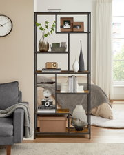 Frontale Ansicht eines hohen, offenen Regals im Industrial-Design mit schwarzem Metallrahmen und Holzböden, dekoriert mit Vasen, Büchern, Boxen und Bildern im Wohn-/Schlafzimmer neben einem Fenster.