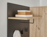 Nahaufnahme einer Kompakt-Garderobe mit einem Regalbrett, auf dem Bücher und eine Box stehen, sowie Haken für Kleidung. Perspektive von der Seite.
