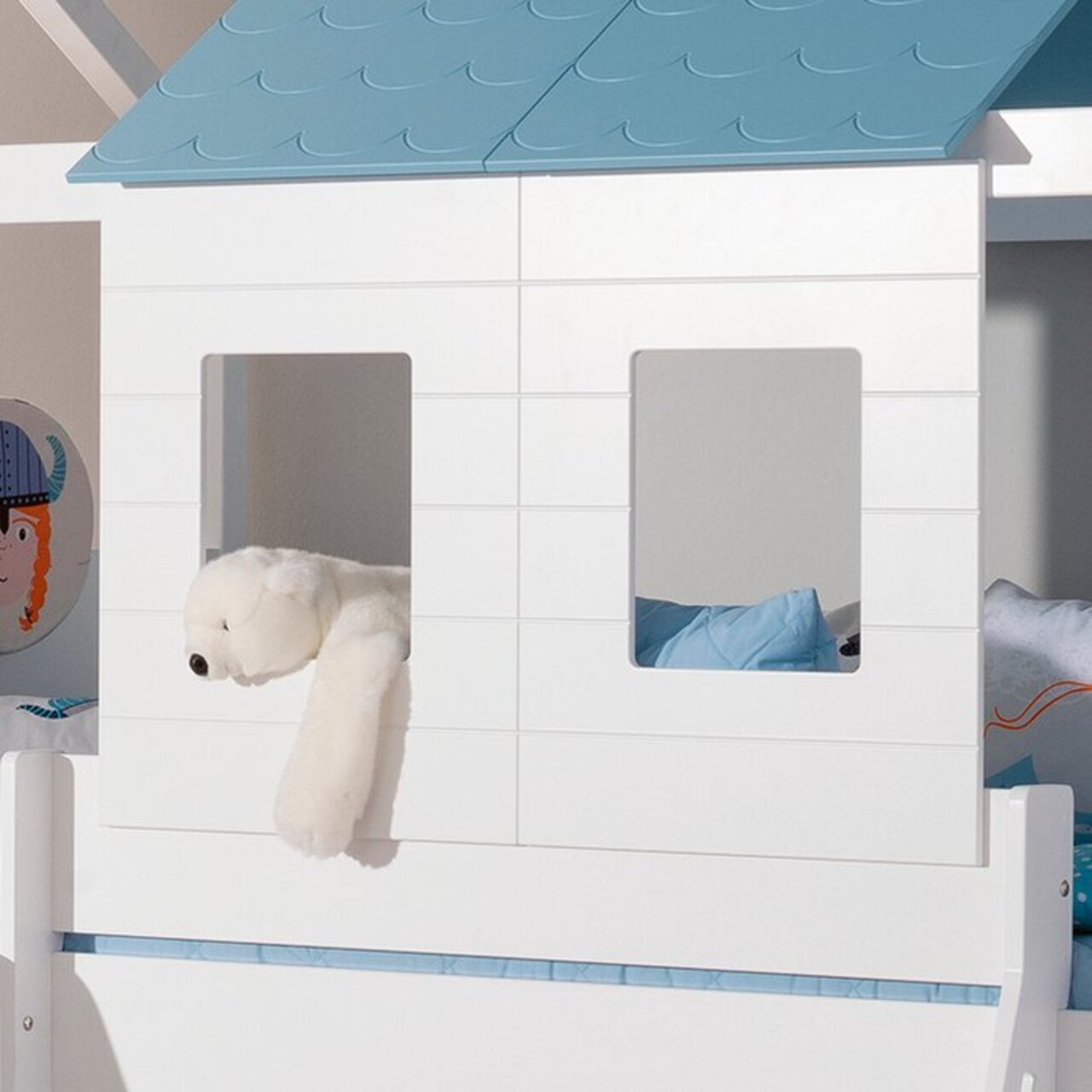 Paidi Fensterpaneele- 2er Set TINY-HOUSE Fensterpaneele-Set in Form eines kleinen Hauses mit blauen Dachpaneelen und zwei rechteckigen Fenstern, aus der Perspektive von vorne betrachtet. Ein weißer Plüschbär hängt aus einem der Fenster.