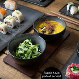 Nahaufnahme eines 29-teiligen Sushi-Tellersets in Anthrazit, präsentiert mit Sushi, Suppe und Gemüse-Dip auf einem Holztisch.