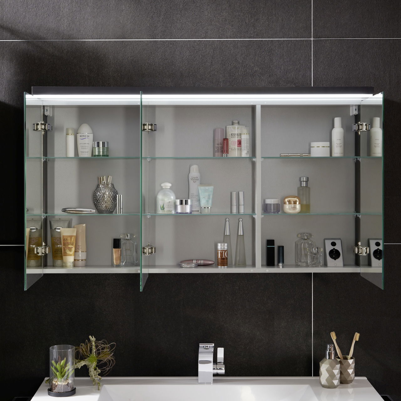 Badezimmerschrank mit Glasregalen, gefüllt mit Pflegeprodukten, aus frontaler Perspektive