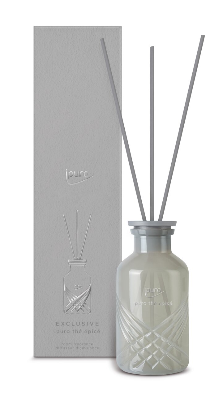 Geurverspreider ipuro thé épicé, 240 ml, in een elegante glazen fles met grijze stokjes, hier afgebeeld in vooraanzicht tegen een bijpassende verpakking.