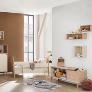 Modernes Lowboard aus Holz in einem Kinderzimmer, frontal fotografiert. Es ist mit Spielzeug und Dekorationen dekoriert und steht auf einem hellen Holzboden.