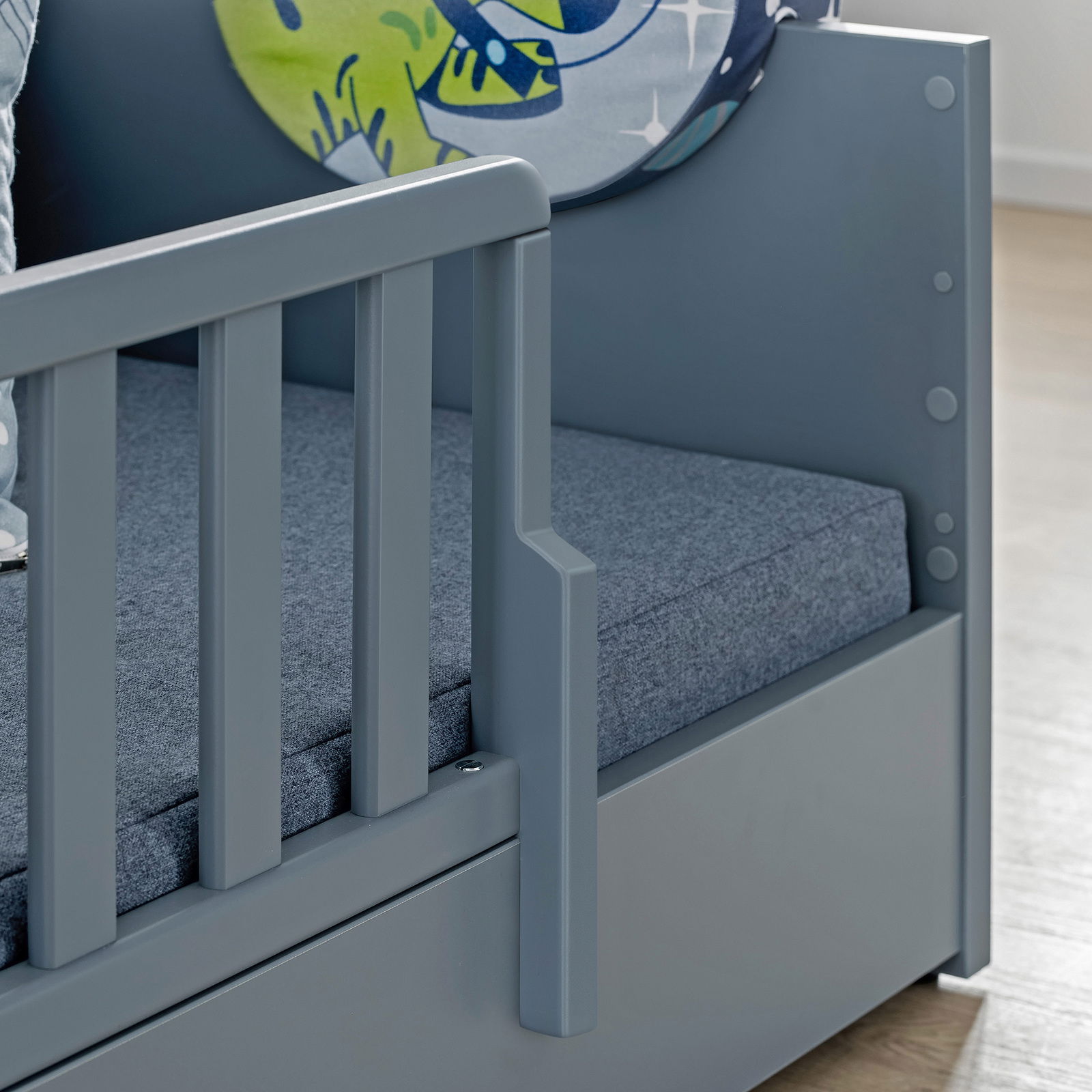 Nahaufnahme eines grauen Bodenbetts mit Rausfallschutz, seitliche Perspektive.