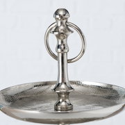 Nahaufnahme einer silbernen Etagere aus der Serie PASSIA von AluBoltze, mit einem eleganten, glänzenden Finish und einem dekorativen Griff. Perspektive von oben auf die obere Ebene.