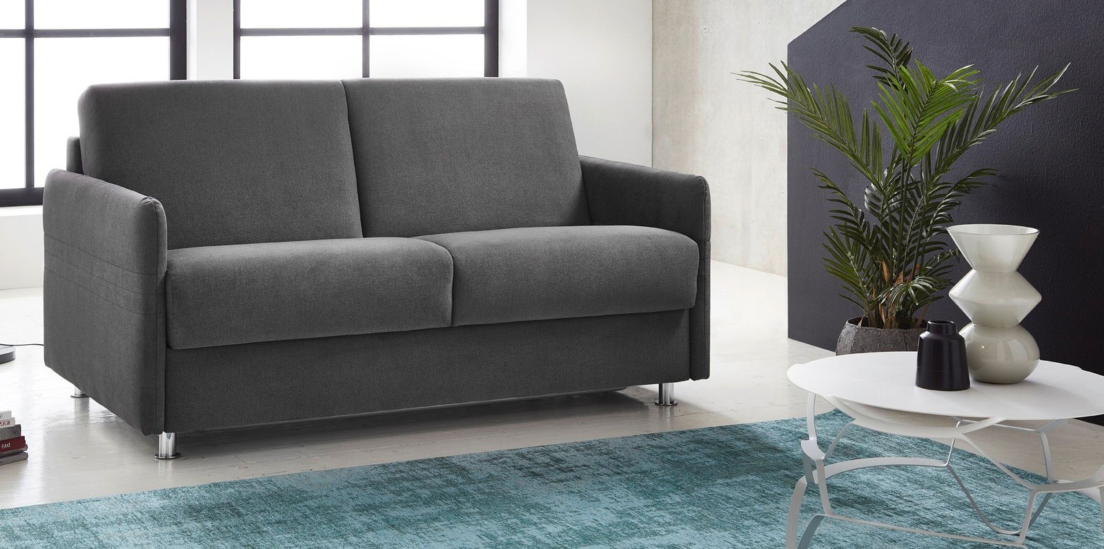 Graues Schlafsofa in modernem Wohnzimmer, seitliche Perspektive.