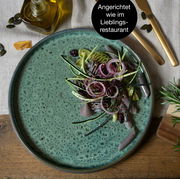 Grüner Teller mit elegant angerichtetem Salat aus Zwiebeln, Zucchini und getrockneten Früchten, von oben fotografiert.