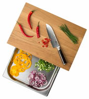 Multifunktionsbrett mit Schublade, darauf rote Chilischoten, ein Messer und Schnittlauch, darunter geschnittenes Gemüse in einer Edelstahlschale, aus der Vogelperspektive.