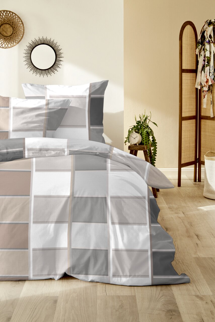 Modernes Bett mit grau-weiß kariertem Bettwäsche-Set und passenden Kissenbezügen in einem hellen Schlafzimmer, Frontansicht leicht schräg von vorn.