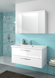 Moderner weißer Badblock mit zwei Schubladen und integriertem Waschbecken, montiert vor einer türkisfarbenen Wand. Perspektive von vorne.
