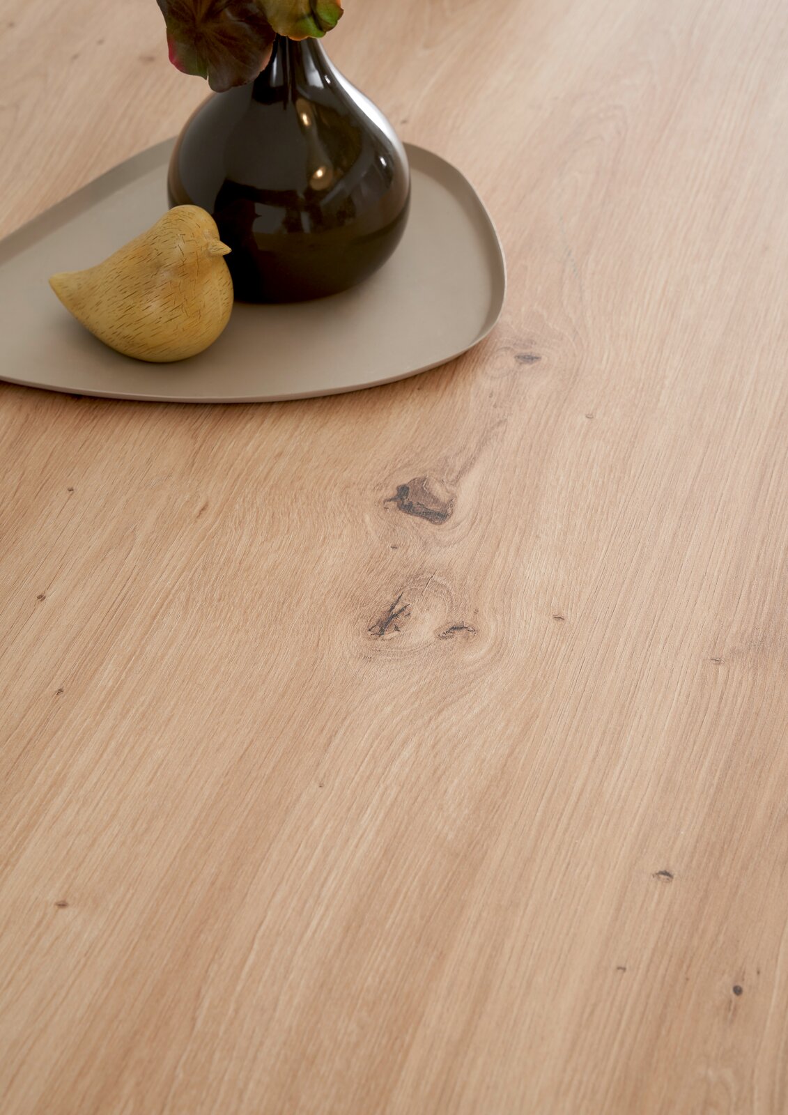 Nahaufnahme einer Kücheninsel mit Holzmaserung, dekoriert mit einer Vase und einem kleinen Vogel aus Keramik auf einem Tablett.