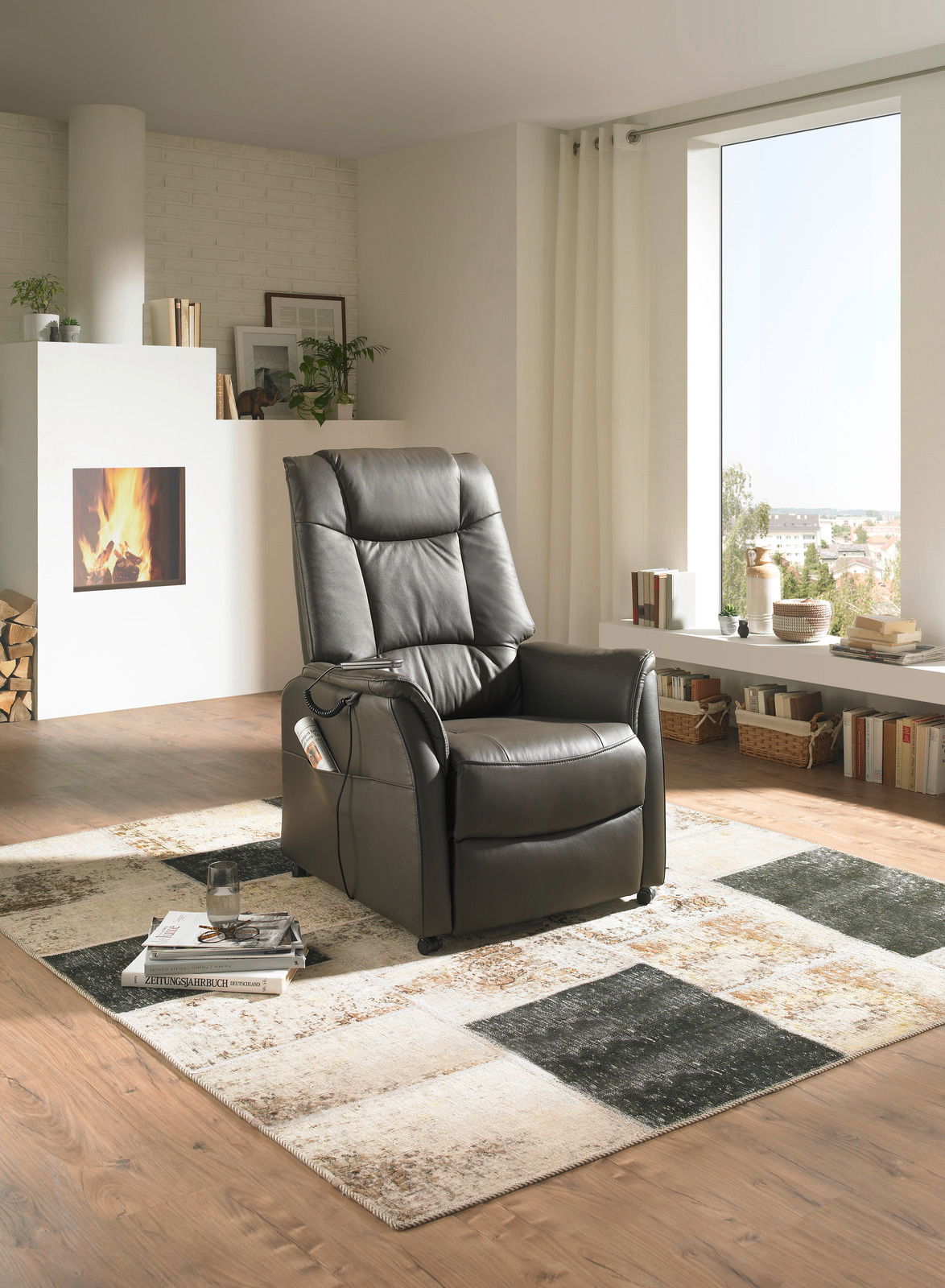 Moderner schwarzer Fernsehsessel in einem gemütlichen Wohnzimmer mit Kamin, von vorne betrachtet.