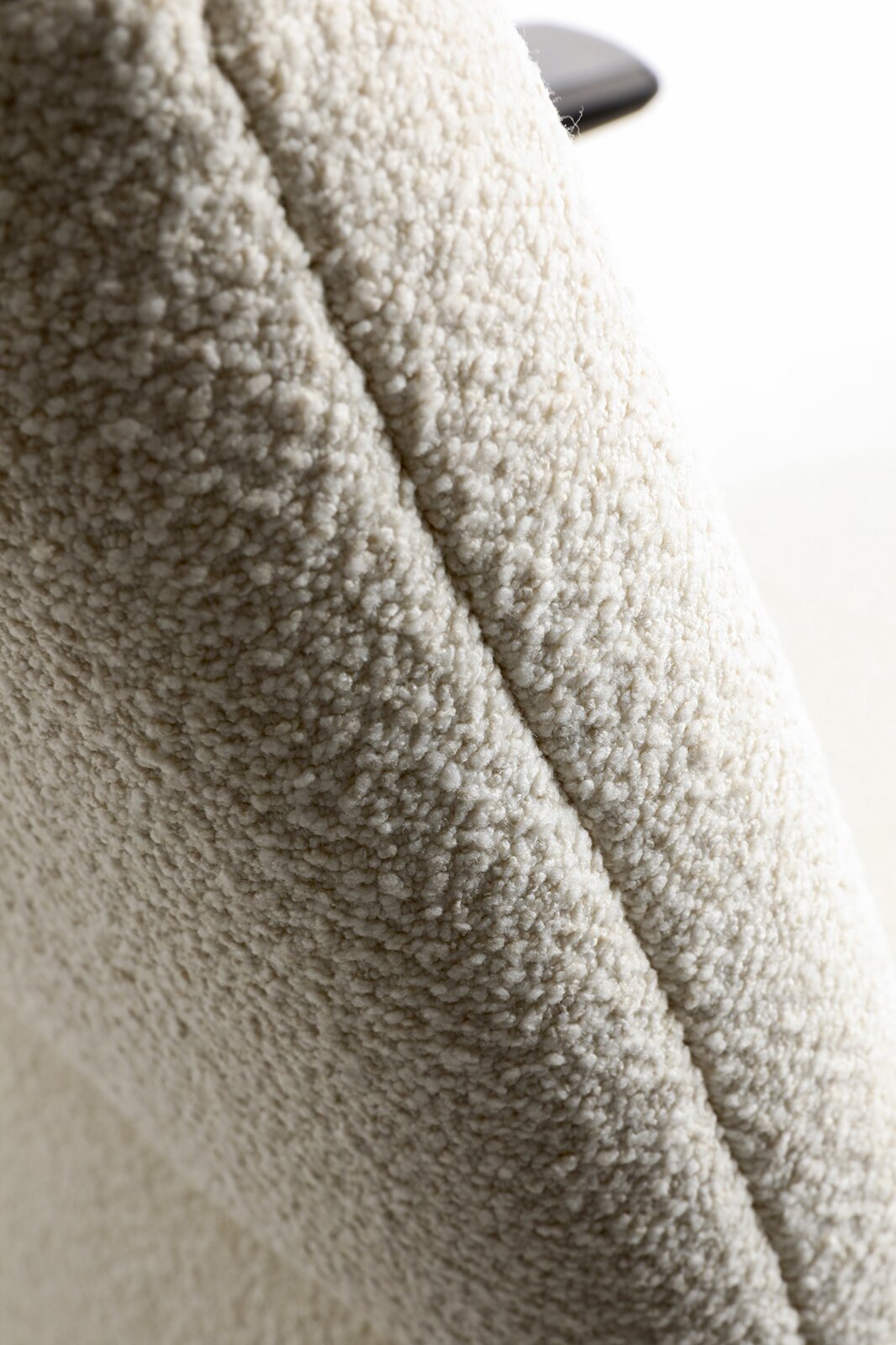Nahaufnahme einer cremefarbenen Teddyfleece-Oberfläche mit weicher, noppiger Struktur; Perspektive: Detailaufnahme/Close-up schräg von der Seite.