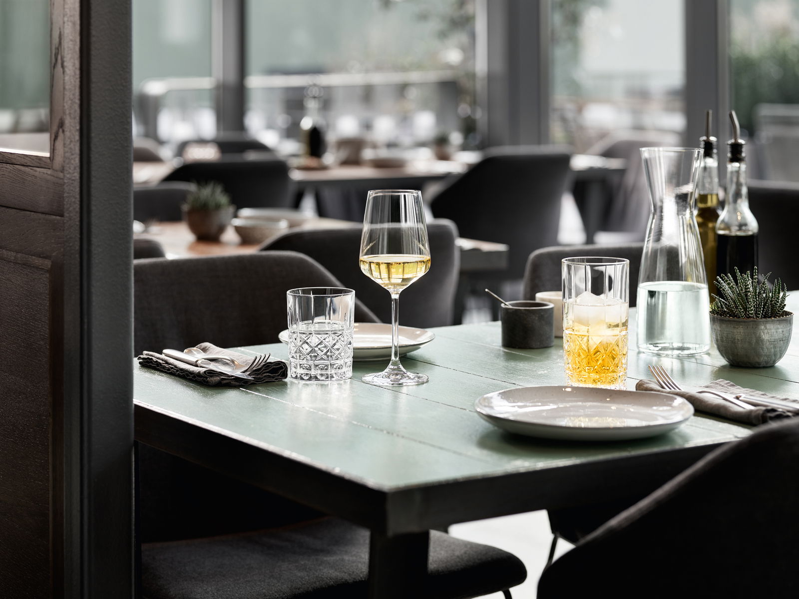 Elegantes Becherset auf einem gedeckten Tisch in einem stilvollen Restaurant, seitliche Perspektive.