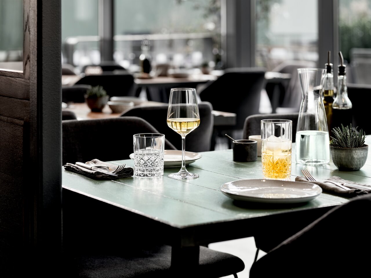 Elegantes Becherset auf einem gedeckten Tisch in einem stilvollen Restaurant, seitliche Perspektive.