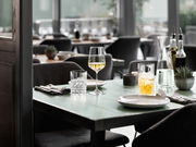 Elegantes Becherset auf einem gedeckten Tisch in einem stilvollen Restaurant, seitliche Perspektive.