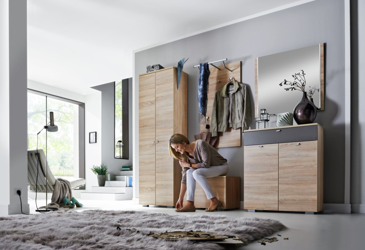 Moderne Garderobenkombination in Holzoptik mit Spiegel, Kleiderhaken und Stauraum, seitliche Perspektive.