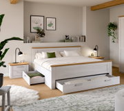 Weißes Doppelbett im Landhausstil mit Holz-Akzenten und zwei ausziehbaren Bettkästen, im Schlafzimmer aus frontaler Perspektive leicht schräg von links fotografiert.