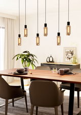 Moderne Pendelleuchte MAIONE mit sieben hängenden Glühbirnen über einem Esstisch, seitliche Perspektive.