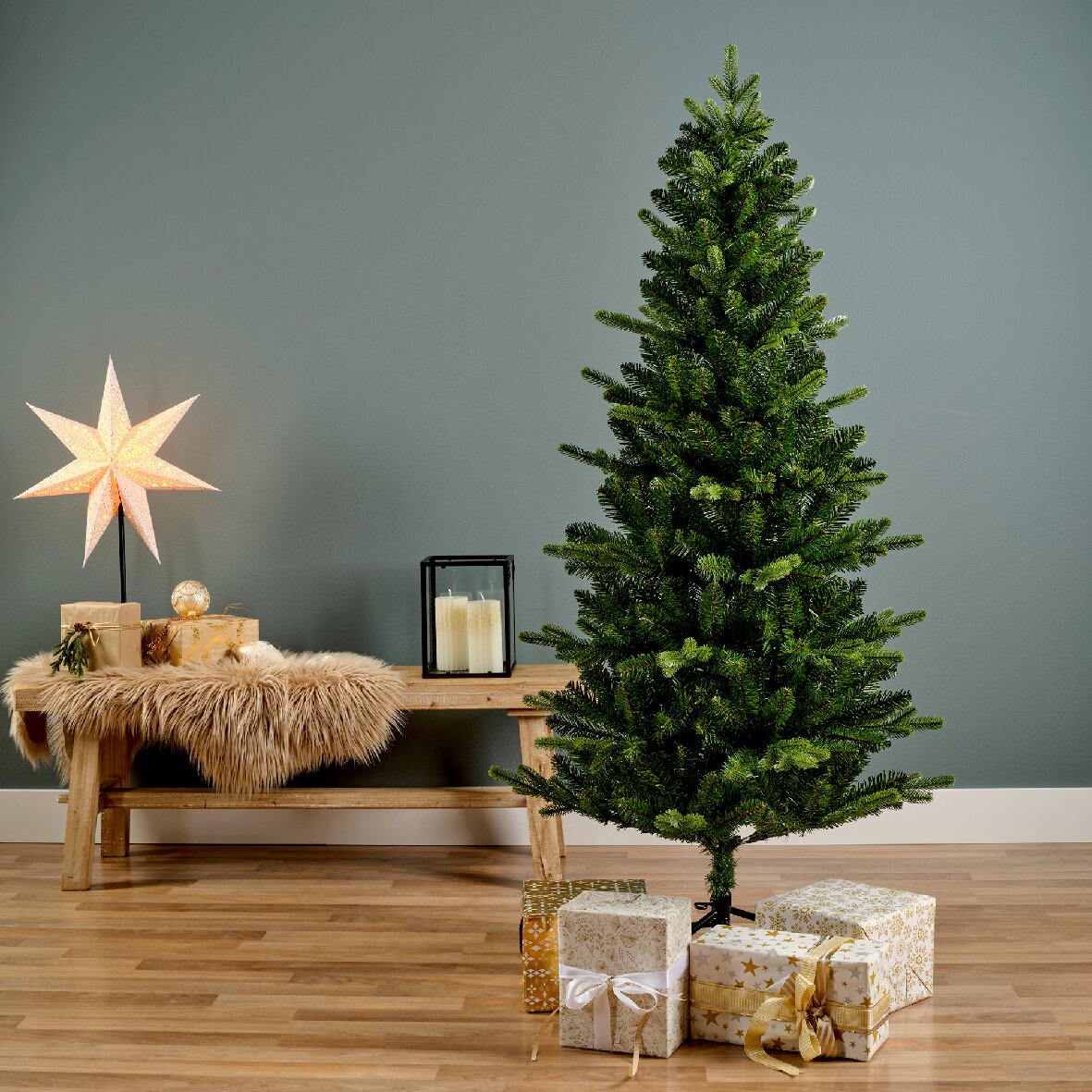 Künstlicher Weihnachtsbaum in einem modernen Wohnzimmer, seitliche Perspektive, umgeben von Geschenken und Dekorationen.