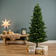 Künstlicher Weihnachtsbaum in einem modernen Wohnzimmer, seitliche Perspektive, umgeben von Geschenken und Dekorationen.