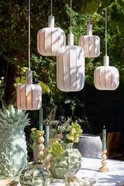 Hängeleuchte in einem Garten, umgeben von grünen Pflanzen und dekorativen Vasen, aus der Perspektive von unten betrachtet.