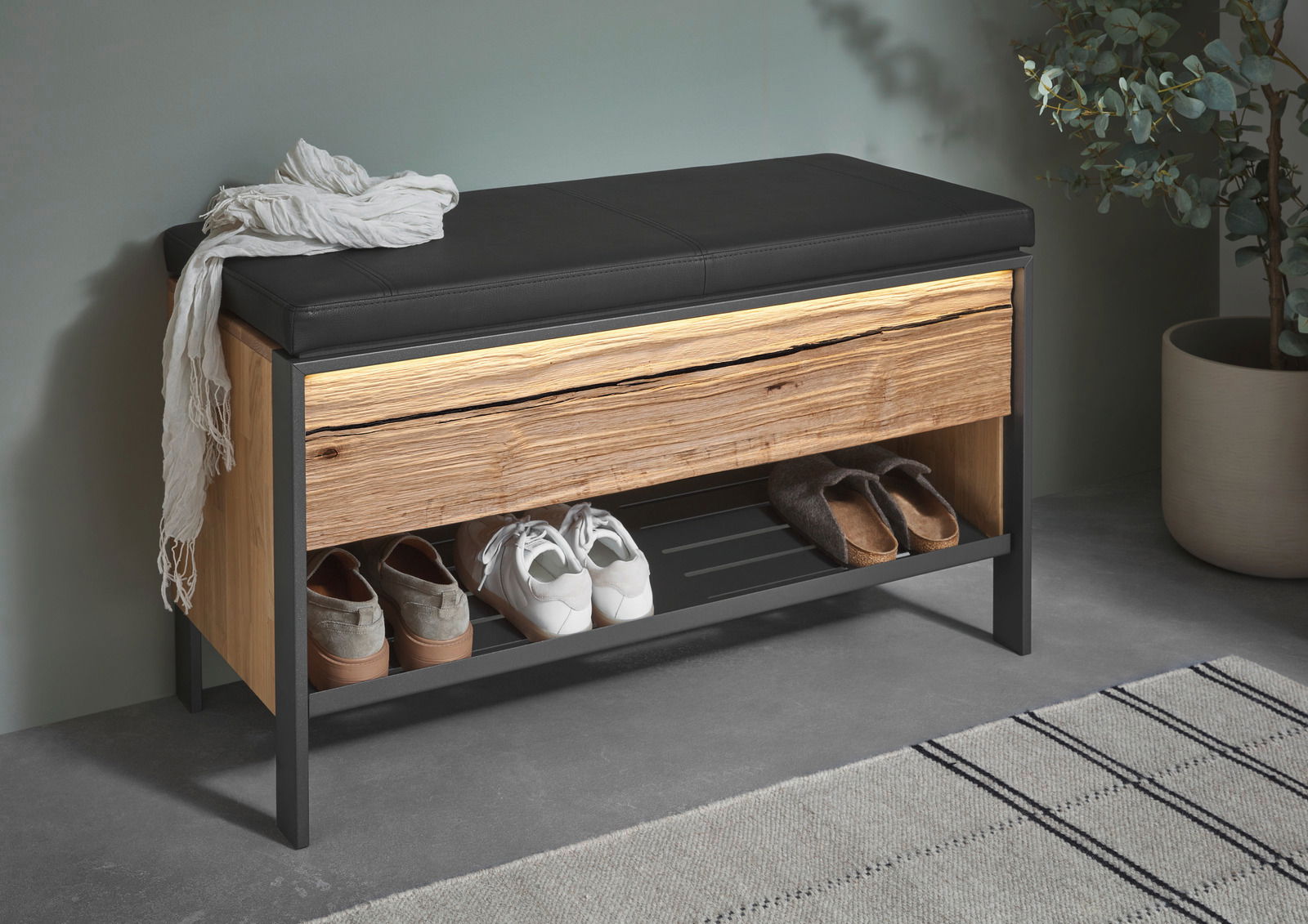 Garderobenbank mit schwarzem Sitzpolster, Holzfront und Schuhablage, seitliche Perspektive