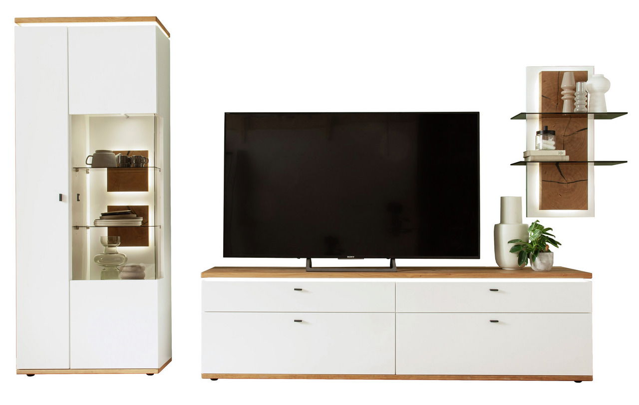 Moderne Wandkombination mit weißem Schrank, großem Fernseher auf einem niedrigen Sideboard und dekorativen Regalen, frontal betrachtet.