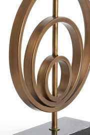 Nahaufnahme eines bronzefarbenen Lampenfußes mit kreisförmigem Design auf einem dunklen Sockel, seitliche Perspektive.