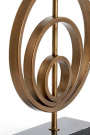 Nahaufnahme eines bronzefarbenen Lampenfußes mit kreisförmigem Design auf einem dunklen Sockel, seitliche Perspektive.