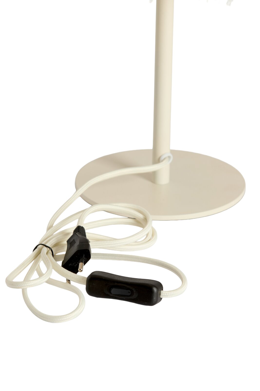 Close-up van de voet van een tafellamp met een witte kabel en een zwarte schakelaar.