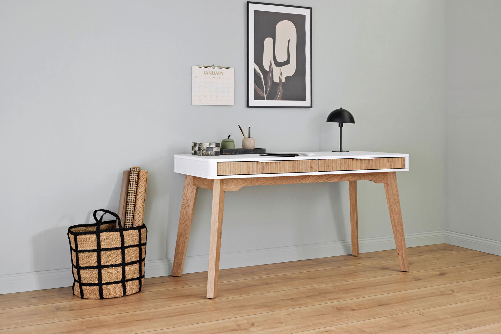 Moderner Schreibtisch aus Holz mit weißer Tischplatte, seitliche Perspektive, dekoriert mit Lampe und Schreibutensilien.