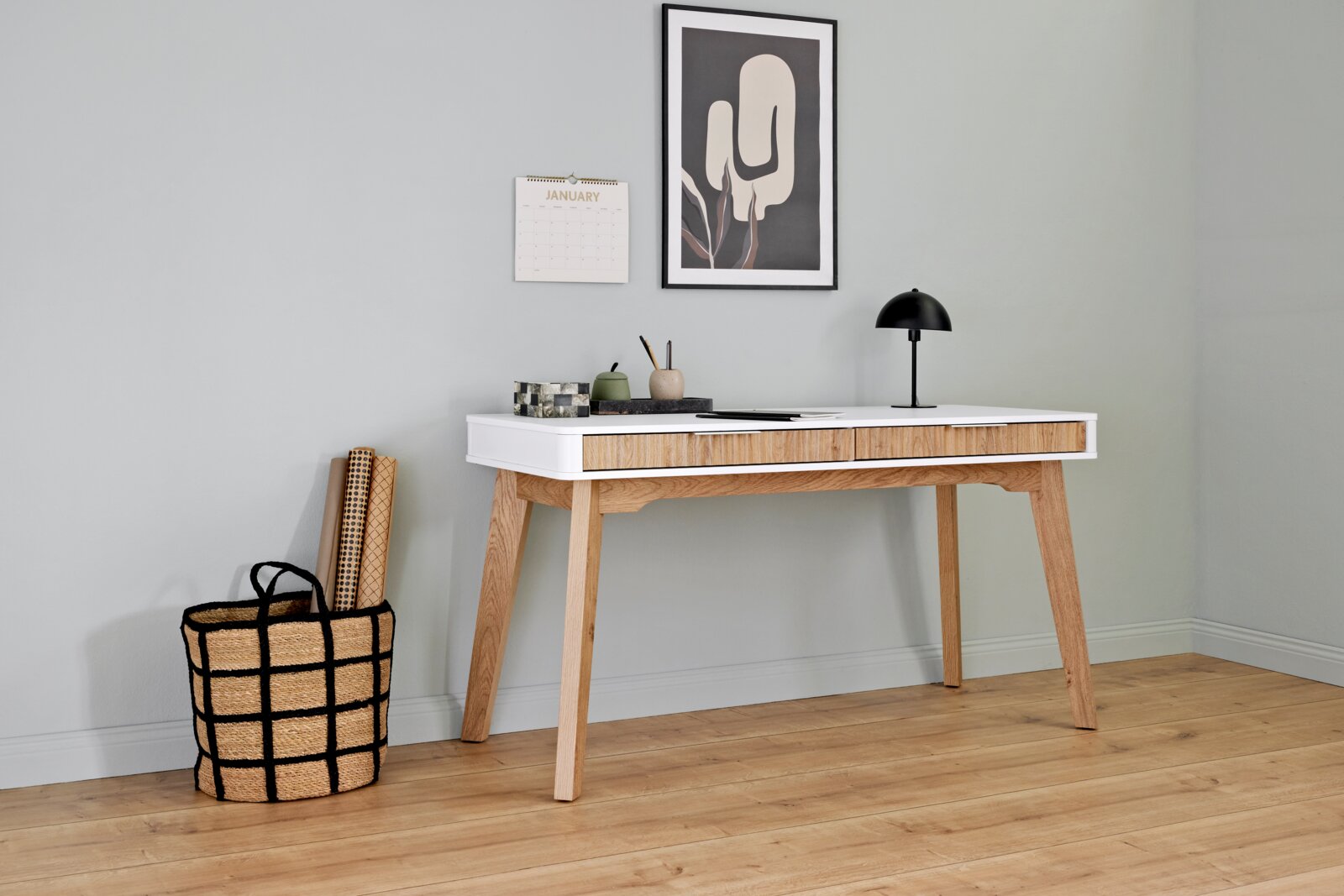Moderner Schreibtisch aus Holz mit weißer Tischplatte, seitliche Perspektive, dekoriert mit Lampe und Schreibutensilien.